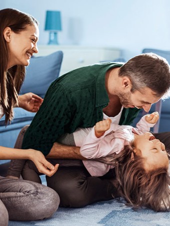 Hausratversicherung: Familie spielt im Wohnzimmer. Hausratversicherung: Familie spielt im Wohnzimmer.