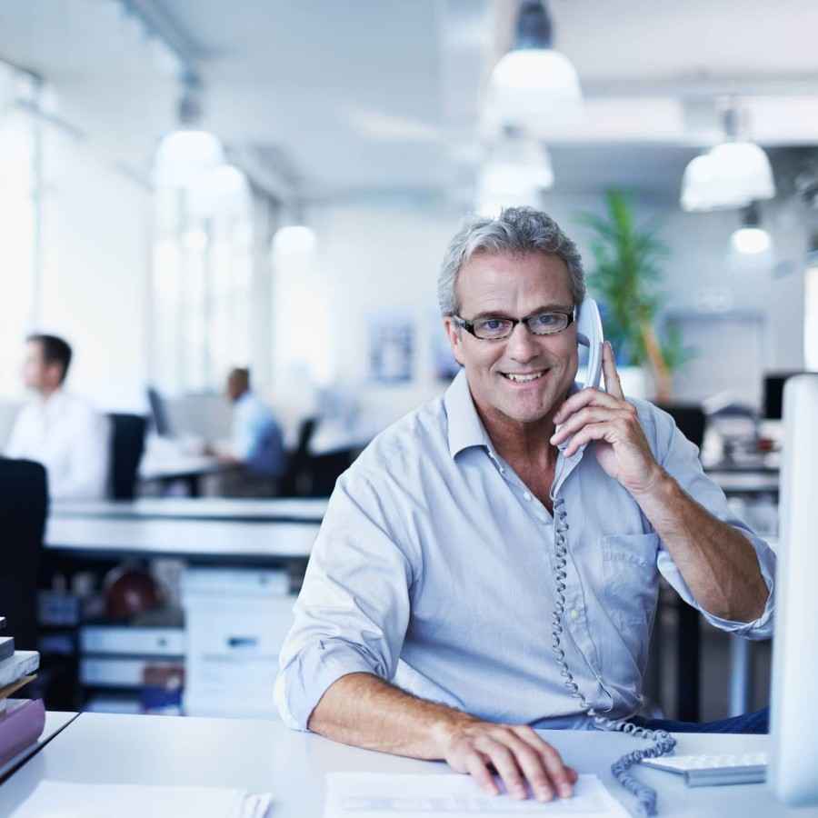 Mann in Großraumbüro am Telefon