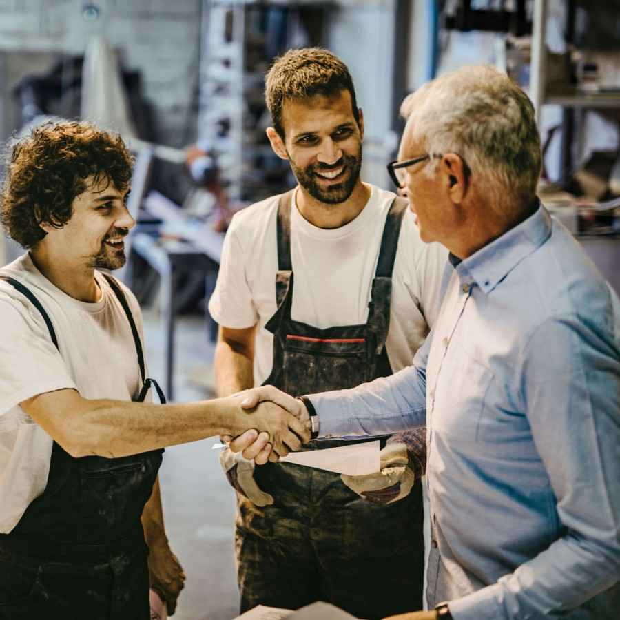 Zwei Bauhandwerker schütteln ihrem Berater die Hand.