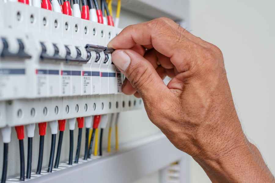 Hand an Sicherungskasten drückt einen Sicherungsschalter