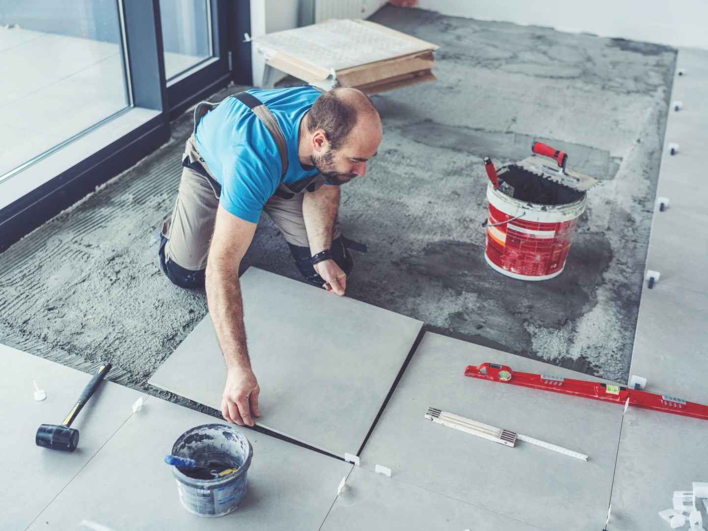 Ein Fliesenleger verlegt quadratische Fliesen.