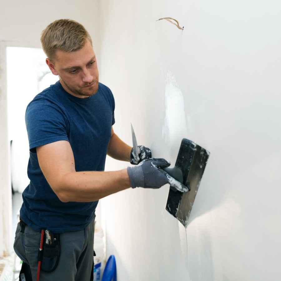 Ein Verputzer verputzt eine weiße Wand
