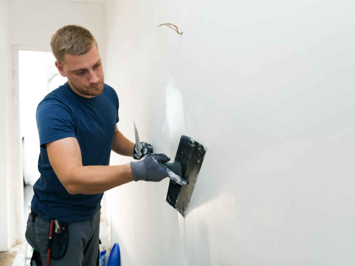 Ein Verputzer verputzt eine weiße Wand