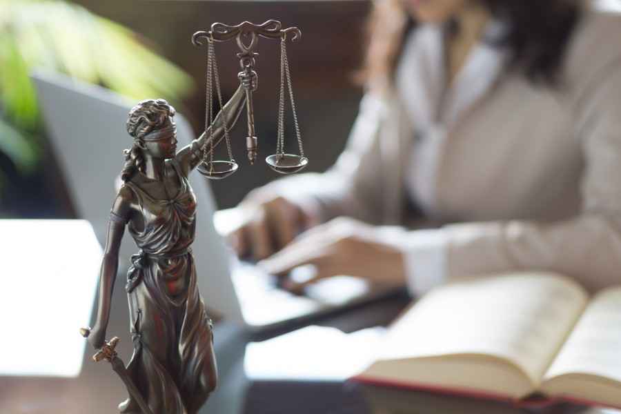 Eine Justitia Figur steht auf einem Schreibtisch. 