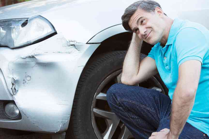 Ein Mann steht neben seinem verunfallten Auto
