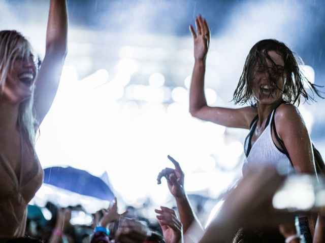 Zwei Frauen feiern auf einem Rock Konzert und es regnet. 