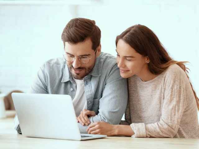 Kapitalanlagen: Paar im Wohnzimmer vor Laptop