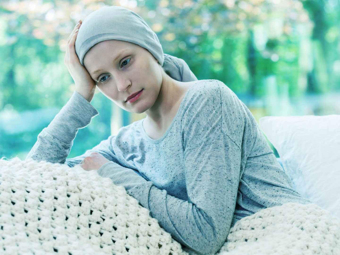 Frau mit Kopftuch sitzt im Bett.