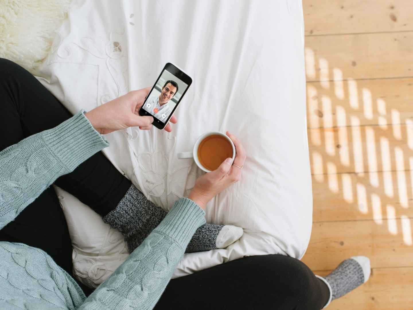 TeleClinic: Kranke Frau nutzt über ihr Smartphone die TeleClinic-App und spricht mit einem Arzt.
