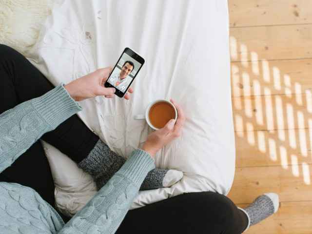 TeleClinic: Kranke Frau nutzt über ihr Smartphone die TeleClinic-App und spricht mit einem Arzt.
