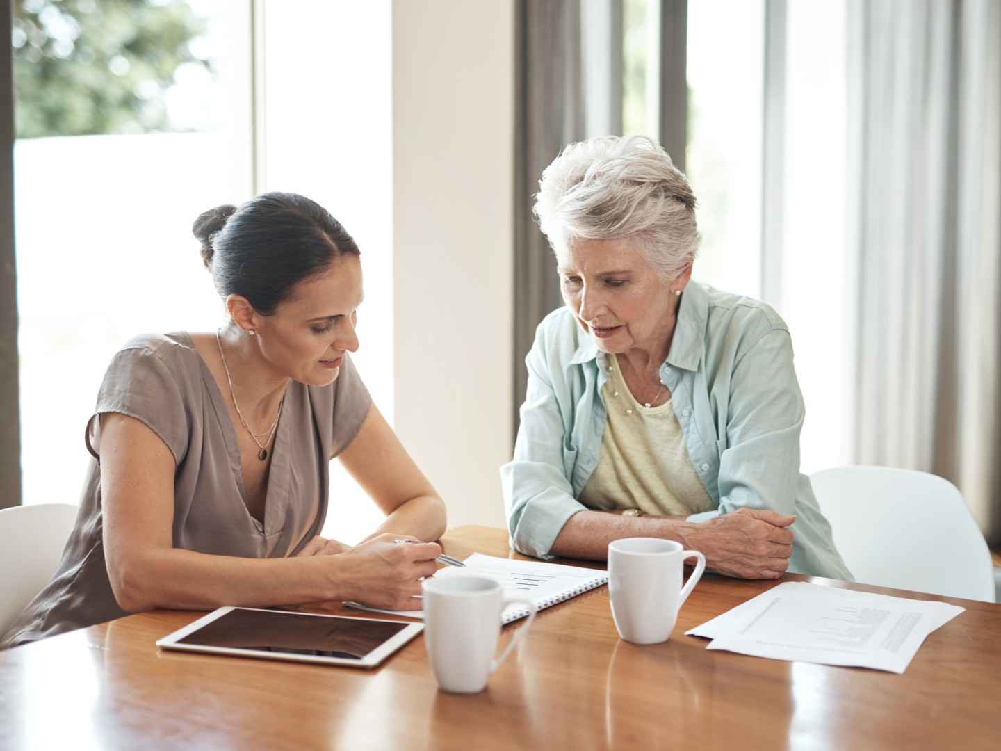 Pflegeberaterin erklärt einer älteren Dame einen Pflegeantrag.