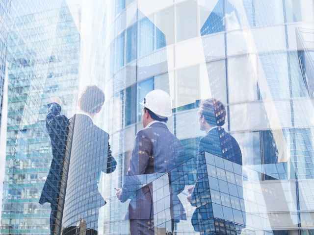 Drei Männer vor einem neuen Glasgebäude
