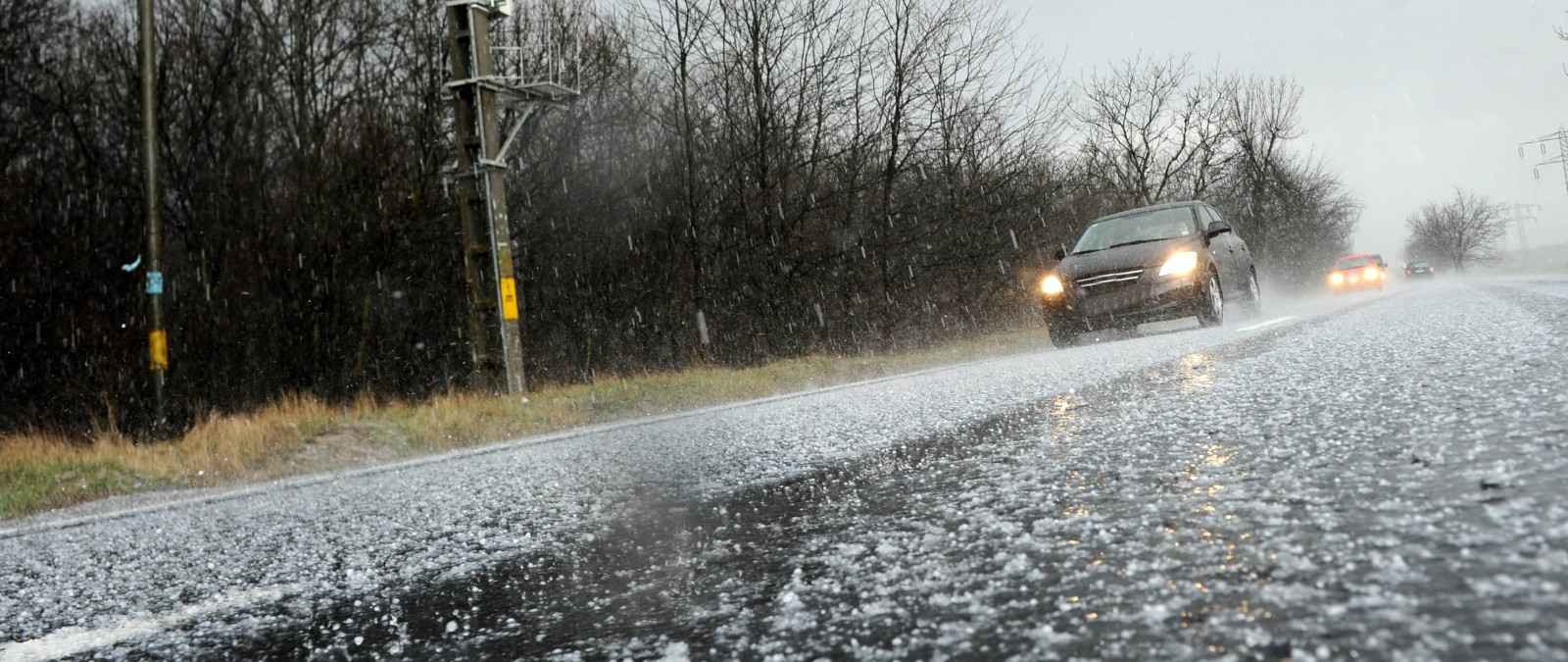 durch Hagel beschädigtes Auto am Fahrbahnrand