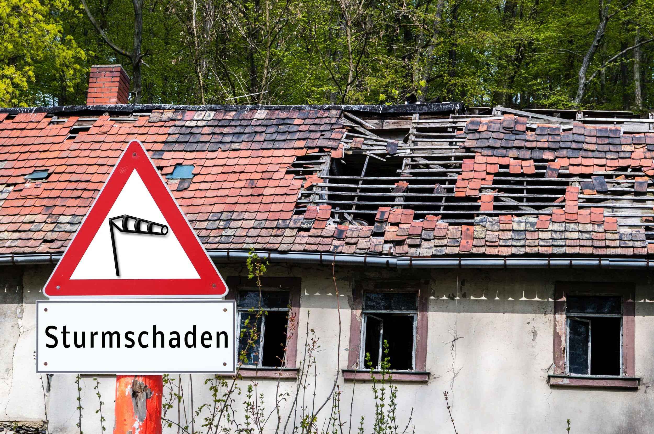 Sturmschaden an einem Haus mit Warnschild davor