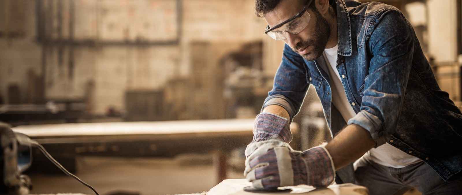 Grundfähigkeitsversicherung: Mann schleift Holzplatte