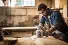Grundfähigkeitsversicherung: Mann schleift Holzplatte