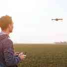 Gothaer Drohnenversicherung: Ein Mann steht auf einem Feld und steuert seine Drohne.
