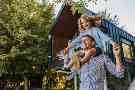 Gothaer Wohngebäudeversicherung: Eine glückliche Familie spielt vor dem Fenster in ihrem Einfamilienhaus.