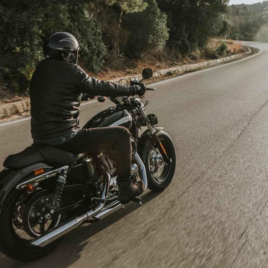 Gothaer Motorradversicherung: Motorradfahrer fährt in der Dämmerung mit seinem Motorrad auf der Straße.