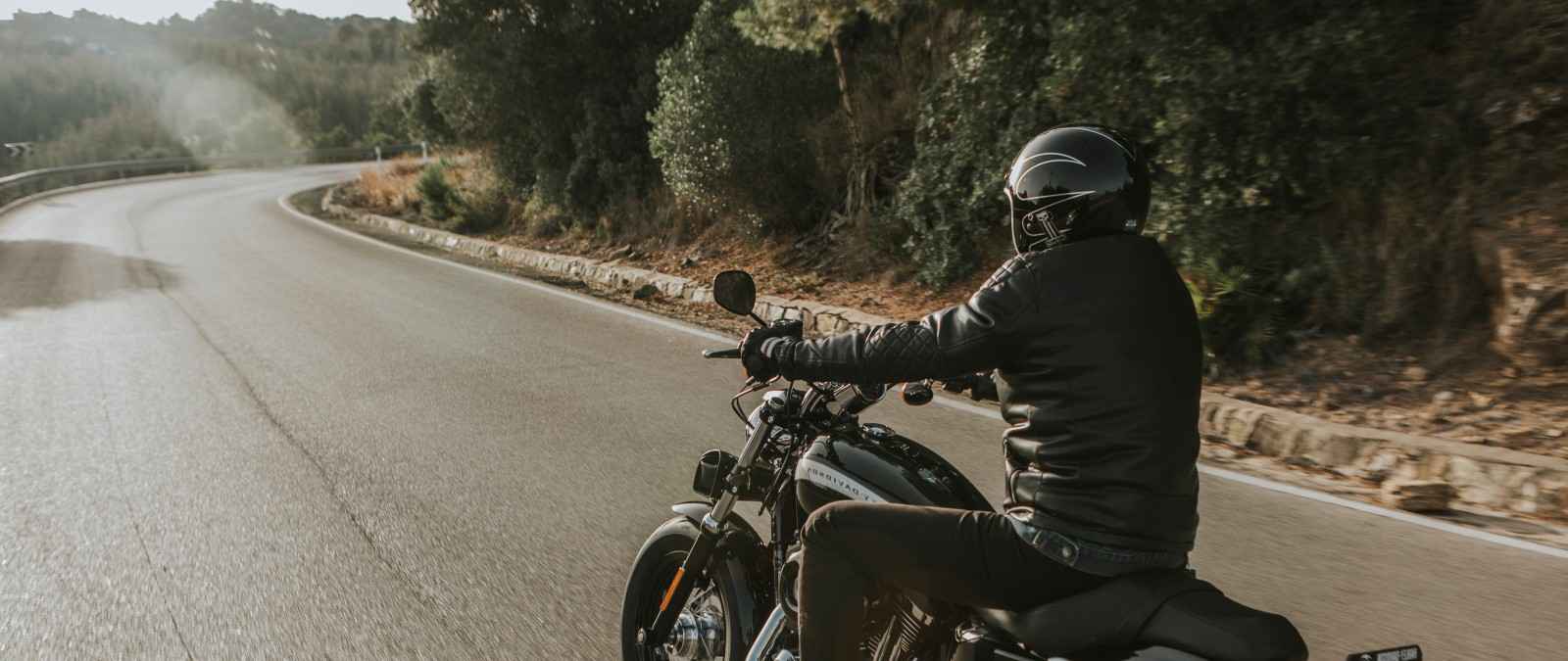 Gothaer Motorradversicherung: Motorradfahrer fährt in der Dämmerung mit seinem Motorrad auf der Straße.