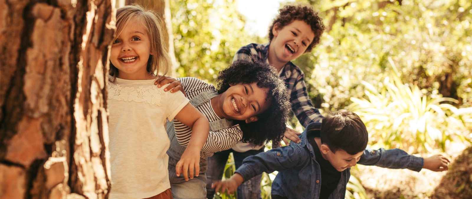Kinderversicherungen Gothaer Kids: 4 Kinder spielen voller Freude im Wald