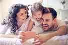 Gothaer Auslandskrankenversicherung für Familien: Eine glückliche Familie macht ein Foto mit einem Handy.