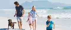 Auslandskrankenversicherung: Eltern spielen mit ihrer kleinen Tochter am Strand.