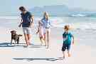 Auslandskrankenversicherung: Eltern spielen mit ihrer kleinen Tochter am Strand.