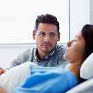 Gothaer Zusatzversicherung: Mann ist froh über die guten Leistungen seiner Zusatzversicherung, während er am Krankenbett seiner Frau wacht.