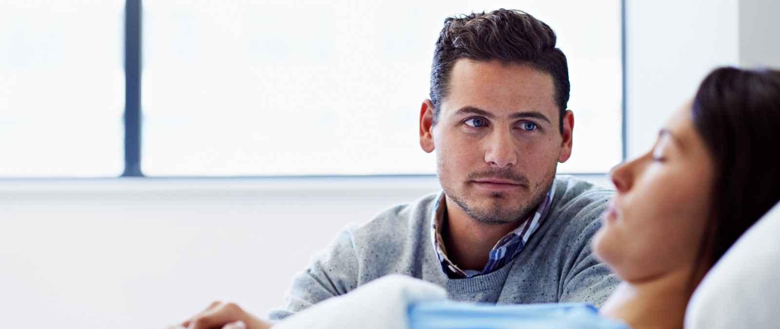 Mann ist froh über die guten Leistungen seiner Krankenzusatzversicherung der Gothaer, während er am Krankenbett seiner Frau wacht.