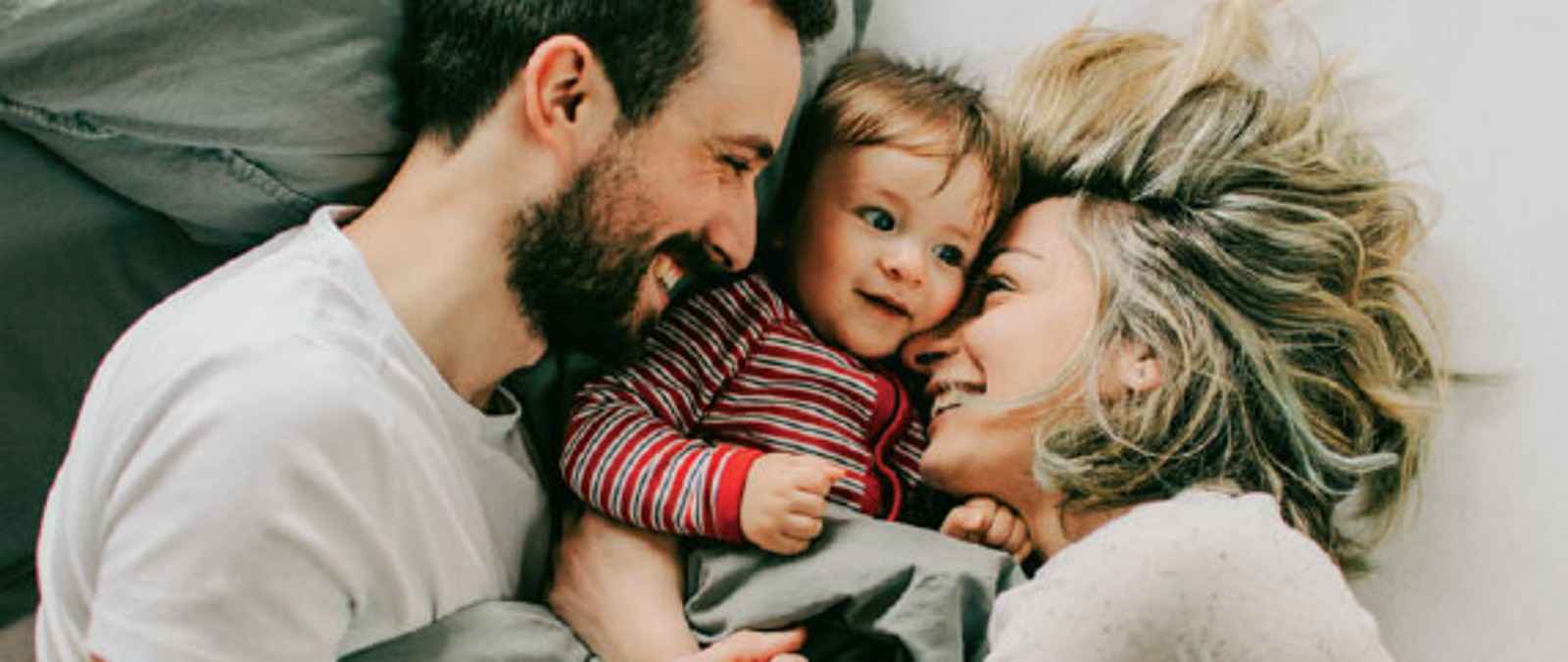 Eltern kuscheln mit Kleinkind im Bett