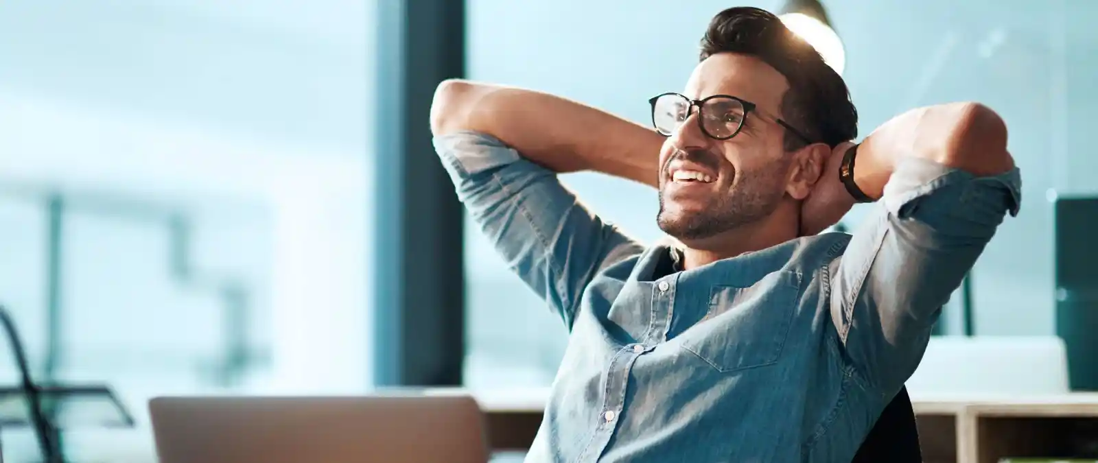 Junger Mann im Büro freut sich über attraktive Steuervorteile bei seiner Rürup-Rente.