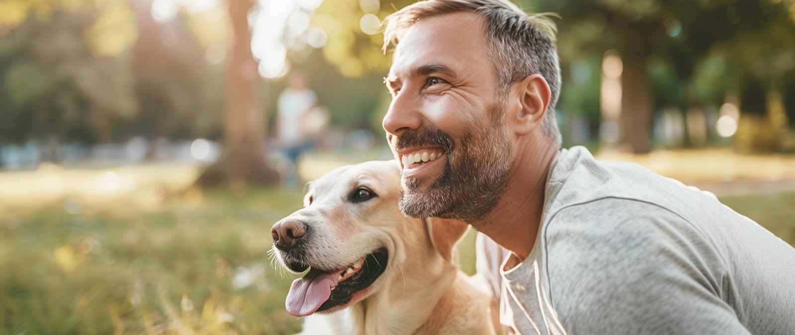 Tierhalterhaftpflicht: Ein junger Mann lacht, weil sein Hund ihm das Gesicht ableckt.