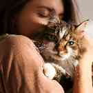 Eine Frau trägt eine Katze auf dem Arm. 
