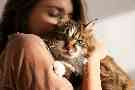 Eine Frau trägt eine Katze auf dem Arm. 