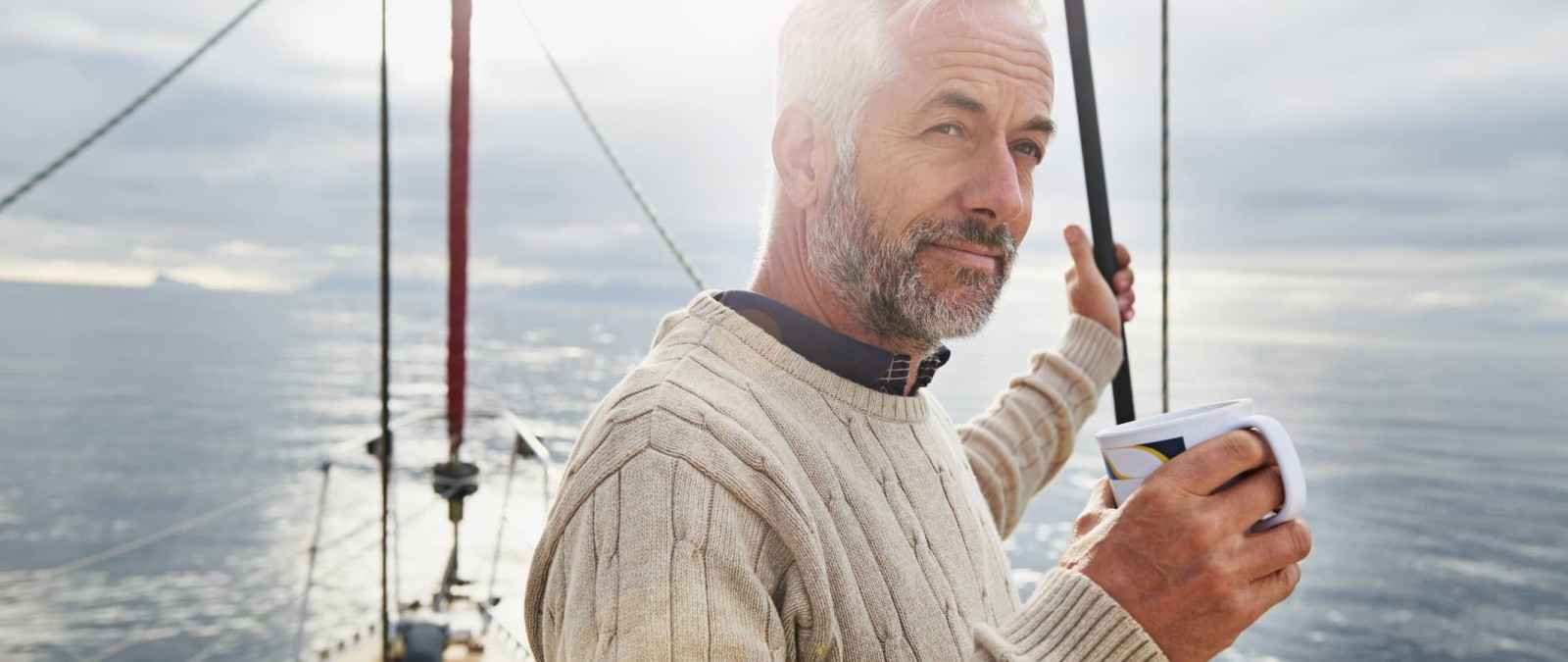 Mann auf seiner Yacht ist gut abgesichert mit der Gothaer Yachtversicherung.
