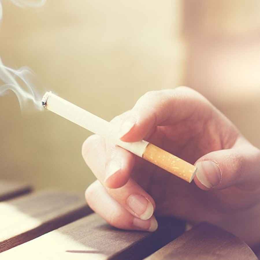 Jemand hält eine brennende Zigarette in der Hand.
