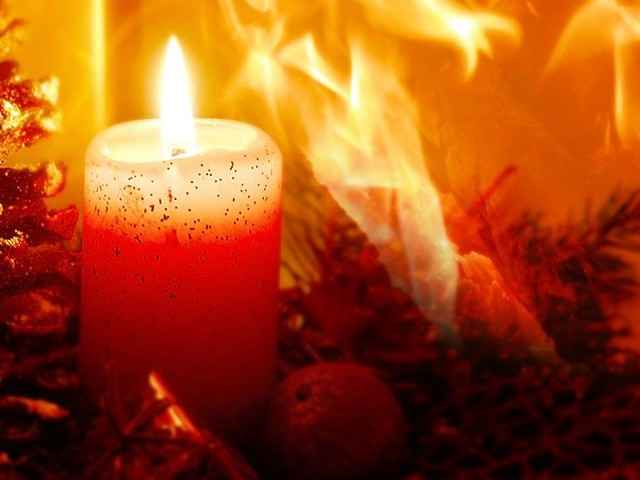 Brennende Kerze mit Feuer im Hintergrund