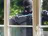 Einbrecher mit ein einer Knippstange vor einem Fenster