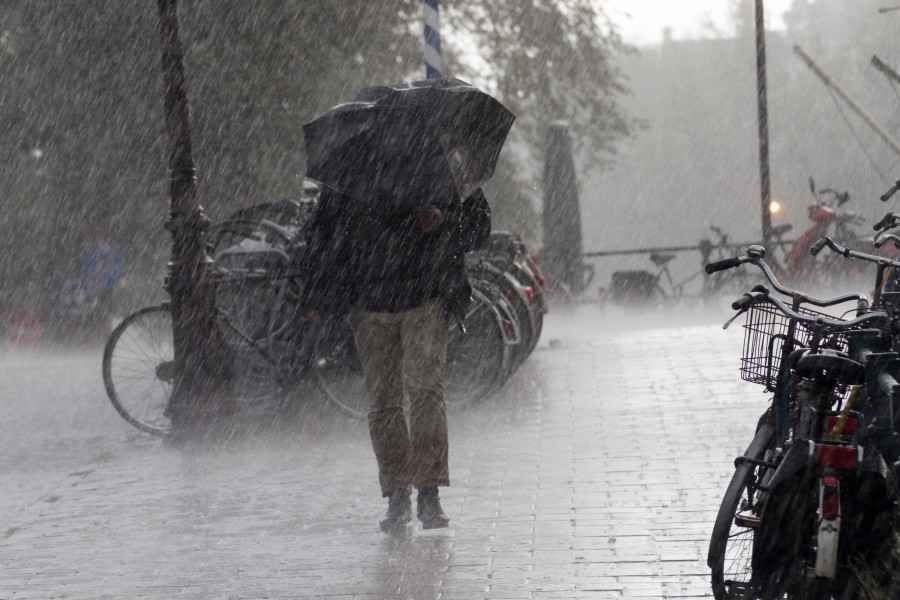 Ein Mann läuft mit Regenschirm durch starken Regen.