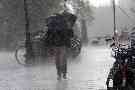 Ein Mann läuft mit Regenschirm durch starken Regen.