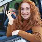 Eine Frau sitzt in Ihrem Auto und hält die Schlüssel in der Hand.