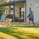 Gothaer Ratgeber: Eine glückliche Familie spielt im Garten Frisbee.