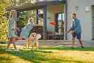 Gothaer Ratgeber: Eine glückliche Familie spielt im Garten Frisbee.