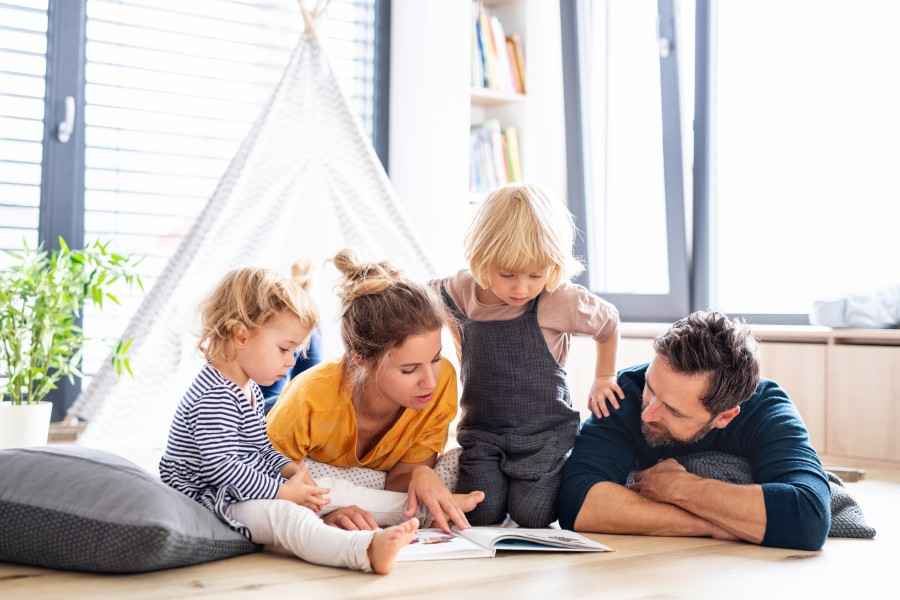 Eltern schauen mit ihren Kindern ein Buch.