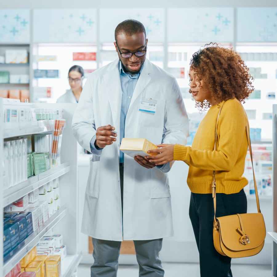 Kundin lässt sich von einem Apotheker beraten, welches Arzneimittel sie kaufen soll.