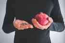 Eisenmangel: Ein Mann hält in der einen Hand ein eisenhaltiges Nahrungsergänzungsmittel und in der anderen Hand einen Granatapfel.