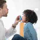 Ein Arzt zeigt einem Kind, wie es inhalieren soll.
