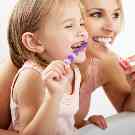 Ein Kind und eine Frau putzen sich die Zähne. 