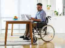 Gothaer Ratgeber Pflegegrad: Ein Rollstuhlfahrer liest sich Unterlagen durch